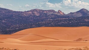 A desert landscape with sand dunes and mountains in the background. - Stylish Family Home in Kanab just 40 Mins to Zion National Park! (Kanab)