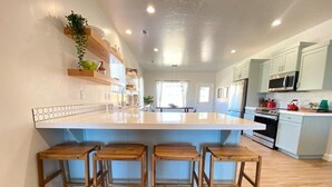 Una cocina moderna con una isla grande, taburetes de madera y electrodomésticos integrados.