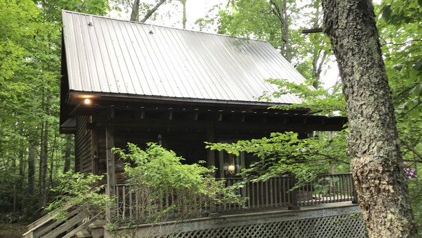 A rustic cabin with a metal roof, wooden staircase, and a lattice fence. - A Hundred Thousand Welcomes! (Newland)