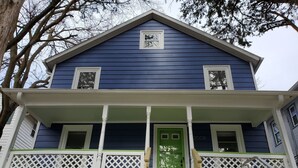 A two-story house with a green front door, white porch railing, and a blue exterior. - Great Location Great Value! 4 bedroom 2 full bath home in East Village (Davenport)