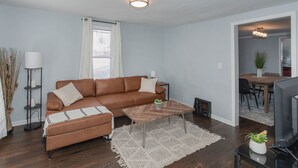 A living room with a brown sectional sofa, a wooden coffee table, and a TV on a stand. - Great Location Great Value! 4 bedroom 2 full bath home in East Village (Davenport)