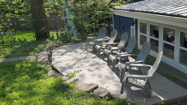 A patio with Adirondack chairs and a covered area with windows. - Great Location Great Value! 4 bedroom 2 full bath home in East Village (Davenport)