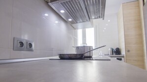 Una cocina moderna con encimera de acero inoxidable, una olla en la hornilla y un ventanal que proporciona luz natural.