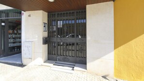 Una entrada de edificio con techo de madera, una puerta de metal y suelo de baldosas.