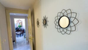Ein Flur mit Essbereich im Hintergrund, einem Wandspiegel und zwei abstrakten Wandbildern.