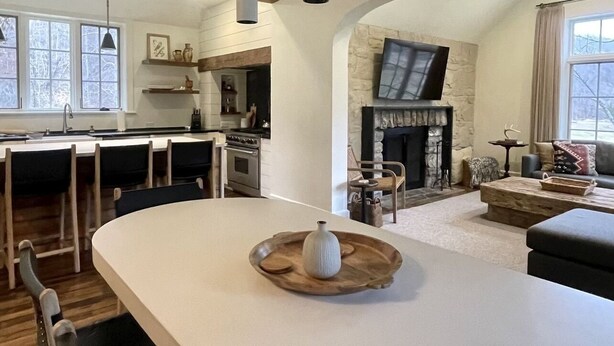 Una cocina amplia con una isla grande, vigas de madera e iluminación colgante.