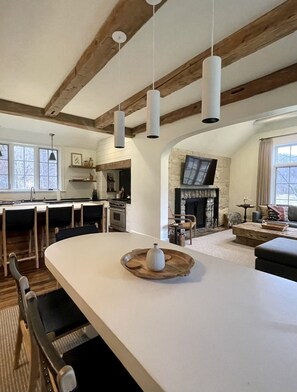 A spacious kitchen with a large island, wooden beams, and hanging pendant lights. - AHMA Cottage 1 (Canton)