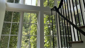 Una habitación amplia con ventanas grandes y una escalera negra.