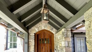 Una entrada de piedra con una puerta de madera, una escalera de piedra y un farol de metal en lo alto.