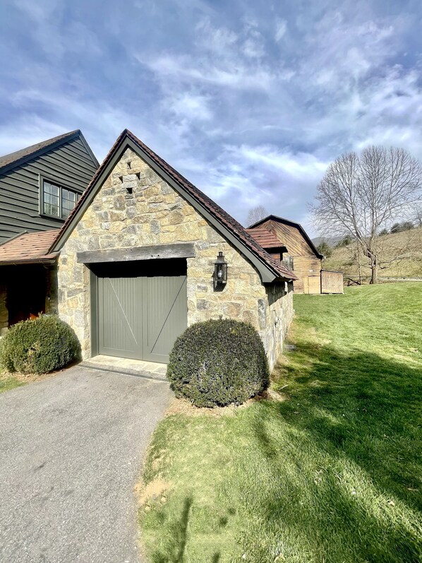 A stone house with a garage, a small lawn, and a tree in the background. - AHMA Cottage 1 (Canton)