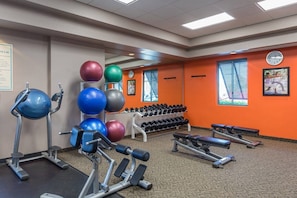 Une salle de sport équipée de matériel d’exercice, d’haltères et de ballons de gymnastique.