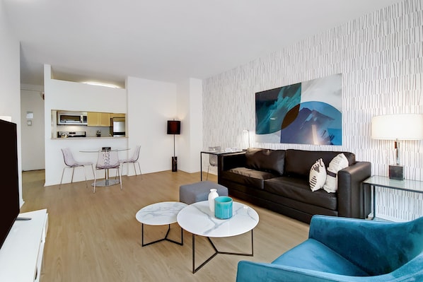 A modern living room with a sofa, two coffee tables, and a dining area with chairs.