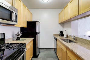 A kitchen with wooden cabinets, a microwave, a refrigerator, a stove, and a sink.