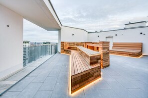Eine Dachterrasse mit Holzbanken und Blick auf die Stadt.