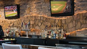 A bar area with stone walls, multiple televisions, and a variety of liquor bottles.