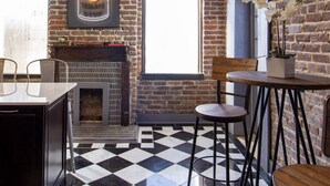 Une cuisine moderne avec un sol à carreaux noirs et blancs, un mur en briques et un tableau encadré représentant la soupe de tomates Campbell.