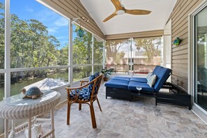 A covered patio with a ceiling fan, wicker furniture, a blue sofa, and a view of a forested area. - New!! Weeki River Retreat Star5vacations (Spring Hill)