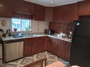 A kitchen with wooden cabinets, a dishwasher, a microwave, and a refrigerator.