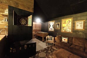 A cozy room with a dartboard, foosball table, and a sofa with decorative pillows.