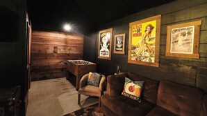 Et hyggeligt rum med et bordtennisbord, en sofa med dekorative puder og vintage plakater på væggen.