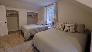 Quarto com duas camas, um guarda-roupa e janela com cortinas.