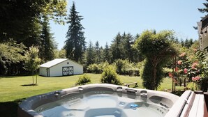 Uma banheira de hidromassagem em um quintal com uma casa e um gramado ao fundo.