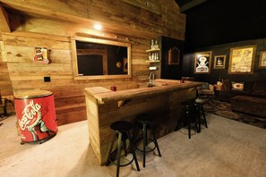 A rustic wooden bar area with a large window, stools, and a Coca-Cola can.