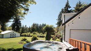 Boblebad i en baghave med en træterrasse, en garage og et hus med en stjerne på garageporten.