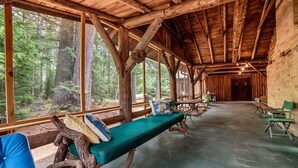Un chalet rustique avec un intérieur en bois, de grandes fenêtres et un banc agrémenté de coussins.