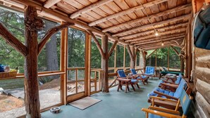 Une cabane en bois dotée de grandes fenêtres, de meubles en bois et offrant une vue sur la forêt.