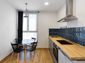 Een koelkast, een oven, kookgerei, borden en bestek, eettafels