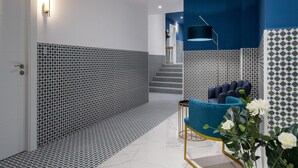Ein modernes Interieur mit gemusterten Wänden, einem blauen Sessel und einer Stehlampe.