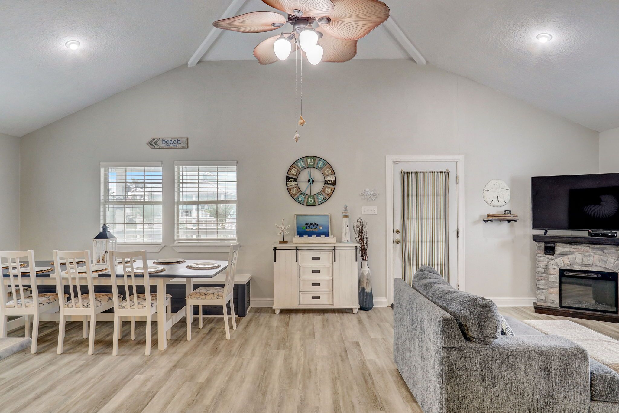 A spacious living room with a dining area, a fireplace, and a ceiling fan.