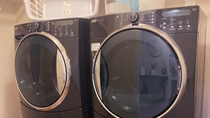Dues rentadores amb càrrega frontal i un cistell a la part superior, situades en una habitació amb paviment de rajola.
