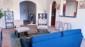 Un saló amb un sofà blau, dos butaques, una taula de centre i un penjoll decoratiu de macramé.