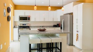 A modern kitchen with white cabinets, a granite countertop, a stainless steel refrigerator, and a gas stove. - Mansión Versatil with a beautiful private pool 🏊‍♀️ 5 min from movies/groceries  (La Romana)