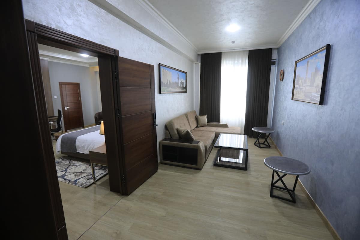 Une chambre d’hôtel avec un lit, un canapé, une table basse et une petite table.