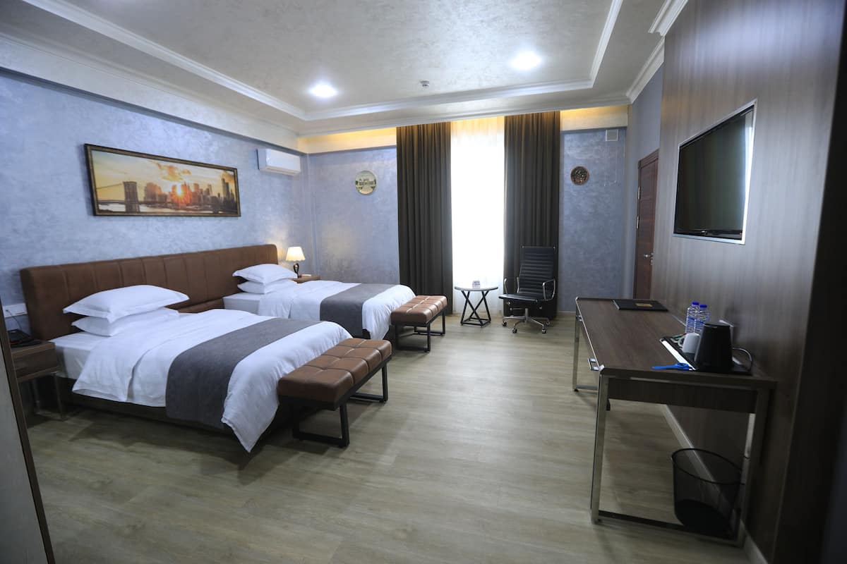 Une chambre d’hôtel avec deux lits, un bureau, une télévision et une petite table.