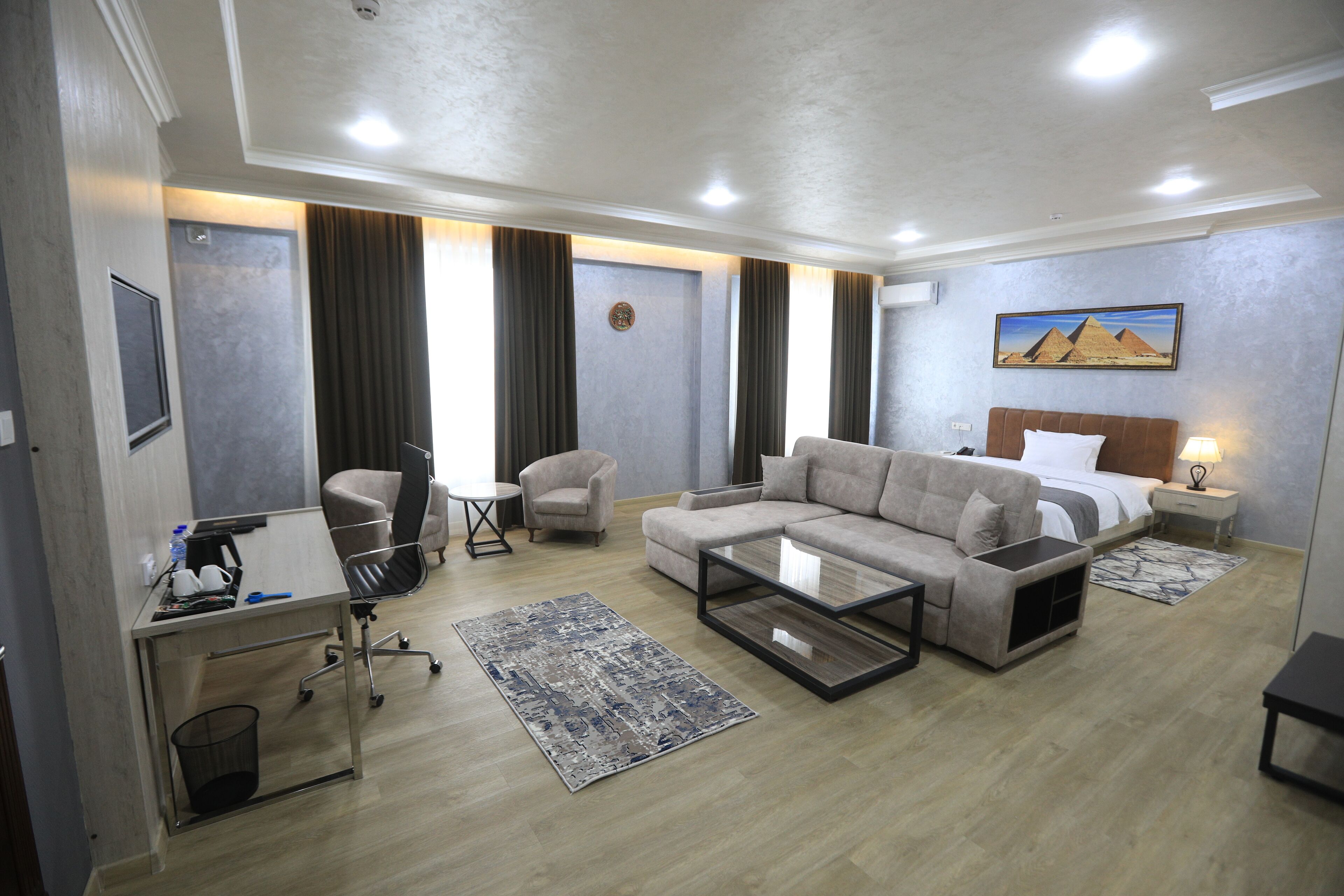 Habitació d'hotel amb sofà, butaca, escriptori i llit amb capçalera.