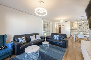 A modern living room with two black leather sofas, a blue armchair, and a round coffee table.
