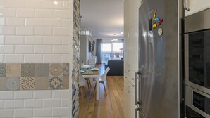 Een moderne keuken met een roestvrijstalen koelkast, een eettafel met stoelen en een achterwand met een patroon.