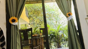 A doorway with green curtains and sunflowers, leading to an outdoor area with a table and chairs. - Enchanted Nest of Love! (Quepos)
