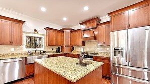 A modern kitchen with wooden cabinets, stainless steel appliances, and a granite countertop island. - Secluded Lodge 8acres Hot Tub, Pingpong kayaks! (Sampson County)