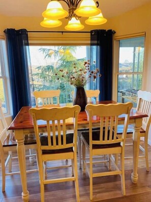 A dining area with a wooden table and chairs, a vase with dried flowers, and a view through large windows. - Cozy, Peaceful, Prescott Getaway (Prescott)
