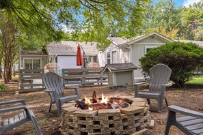 A backyard with a fire pit, outdoor chairs, and a wooden deck.