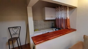 A compact kitchen with a wooden countertop, a sink, and cabinets. There is a chair and a cushion in the foreground. - Lena Cottage - 10km from Nanyuki Town towards Timau (Nanyuki)
