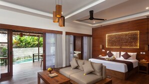 A modern hotel room with a sofa, a bed, a ceiling fan, and a view of a pool and greenery. - Manah Shanti Suites by GenuineHost (Ubud)