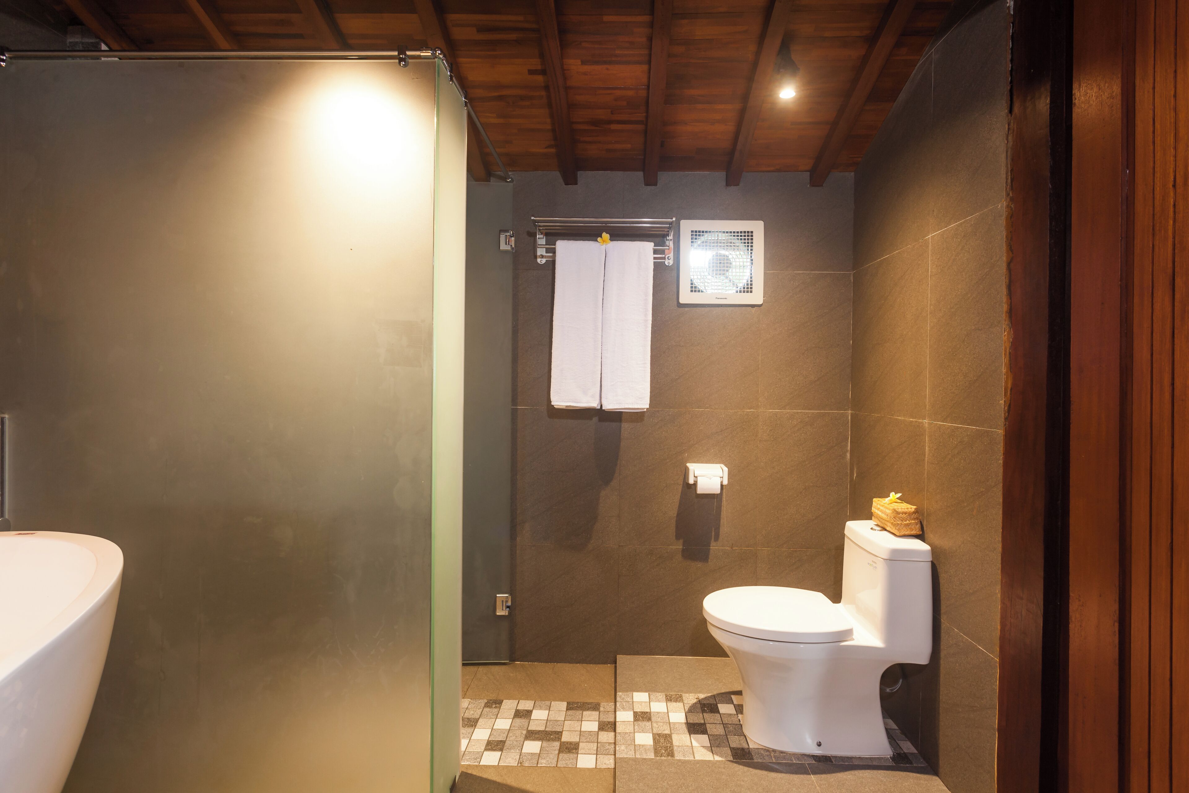 A bathroom with a shower, toilet, and a towel rack.