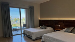 Ett hotellrum med två sängar, en balkong med utsikt över poolen och en sänggavel i trä.