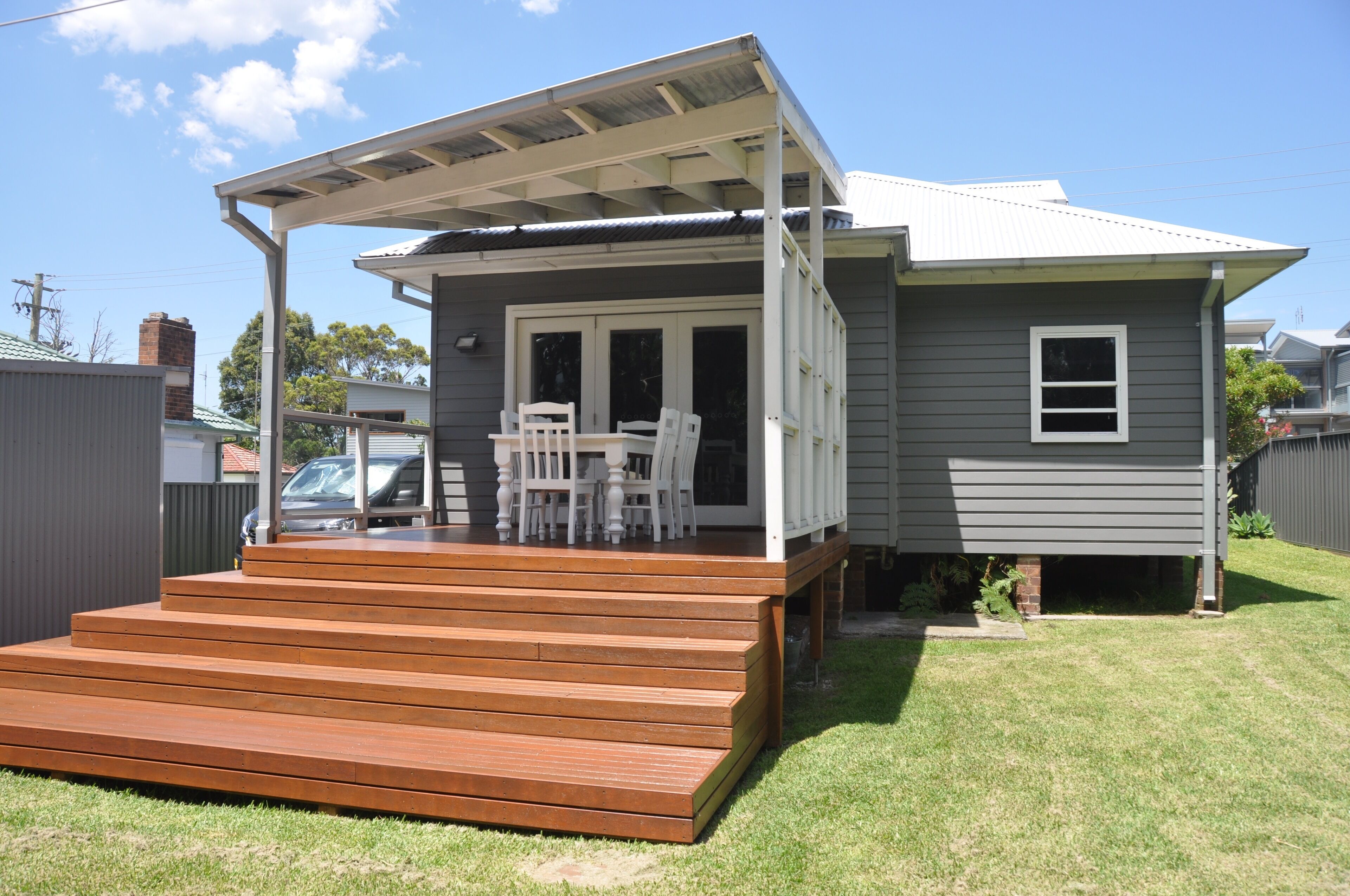 A house with a covered porch, a set of wooden steps leading to the entrance, and a small garden area.